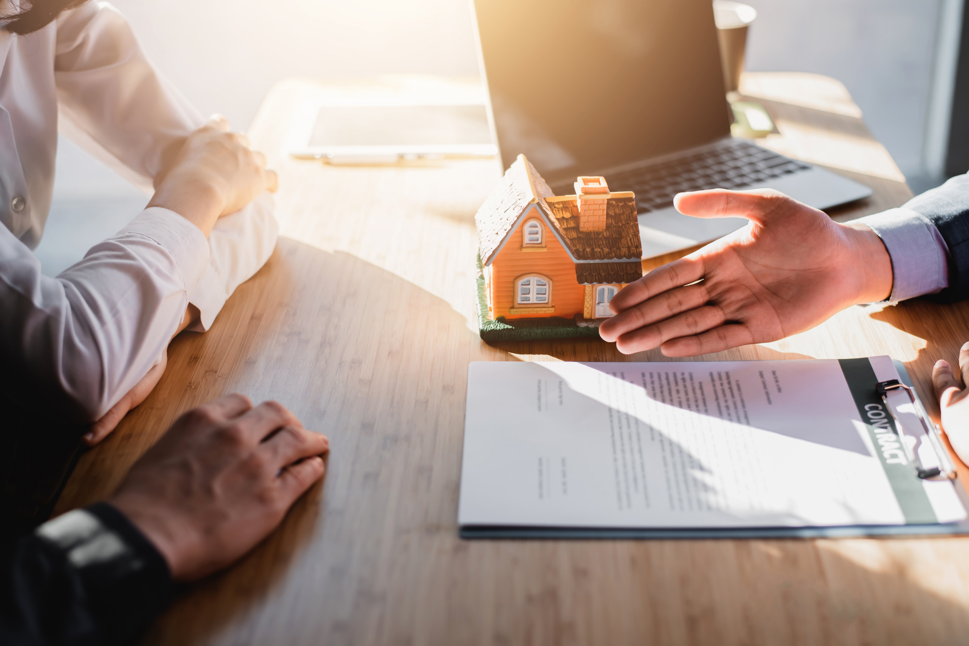A man is shaking hands with a real estate agent while sitting at a table.