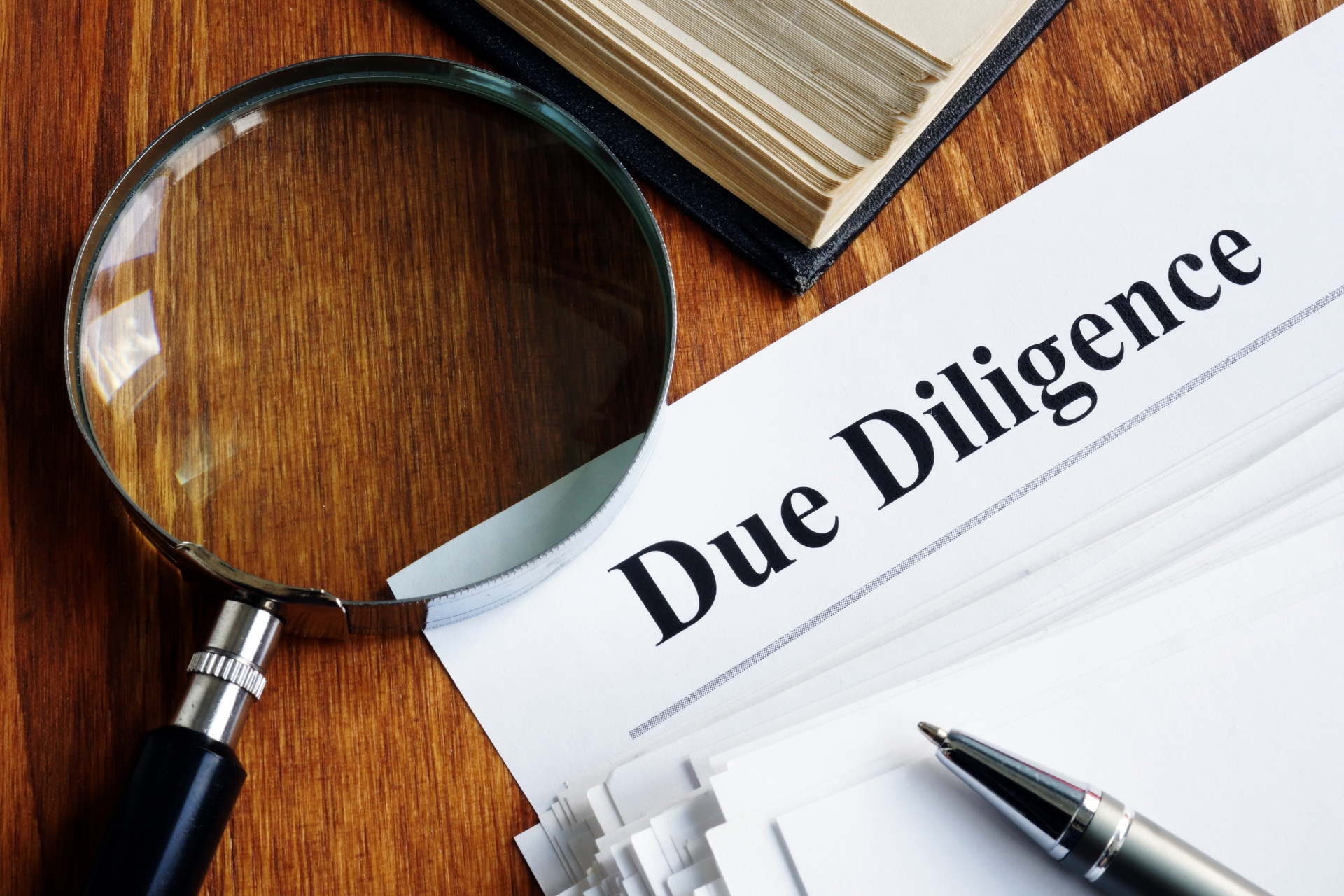 A magnifying glass is sitting on top of a piece of paper that says due diligence.
