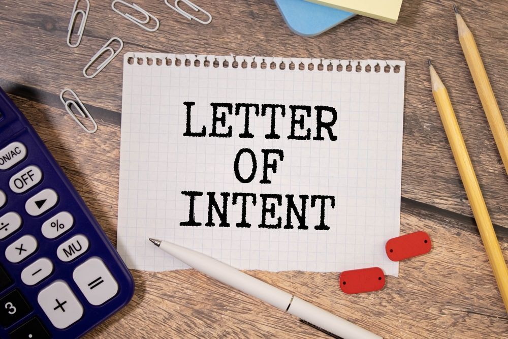 A letter of intent is written on a piece of paper next to a calculator and pencils.