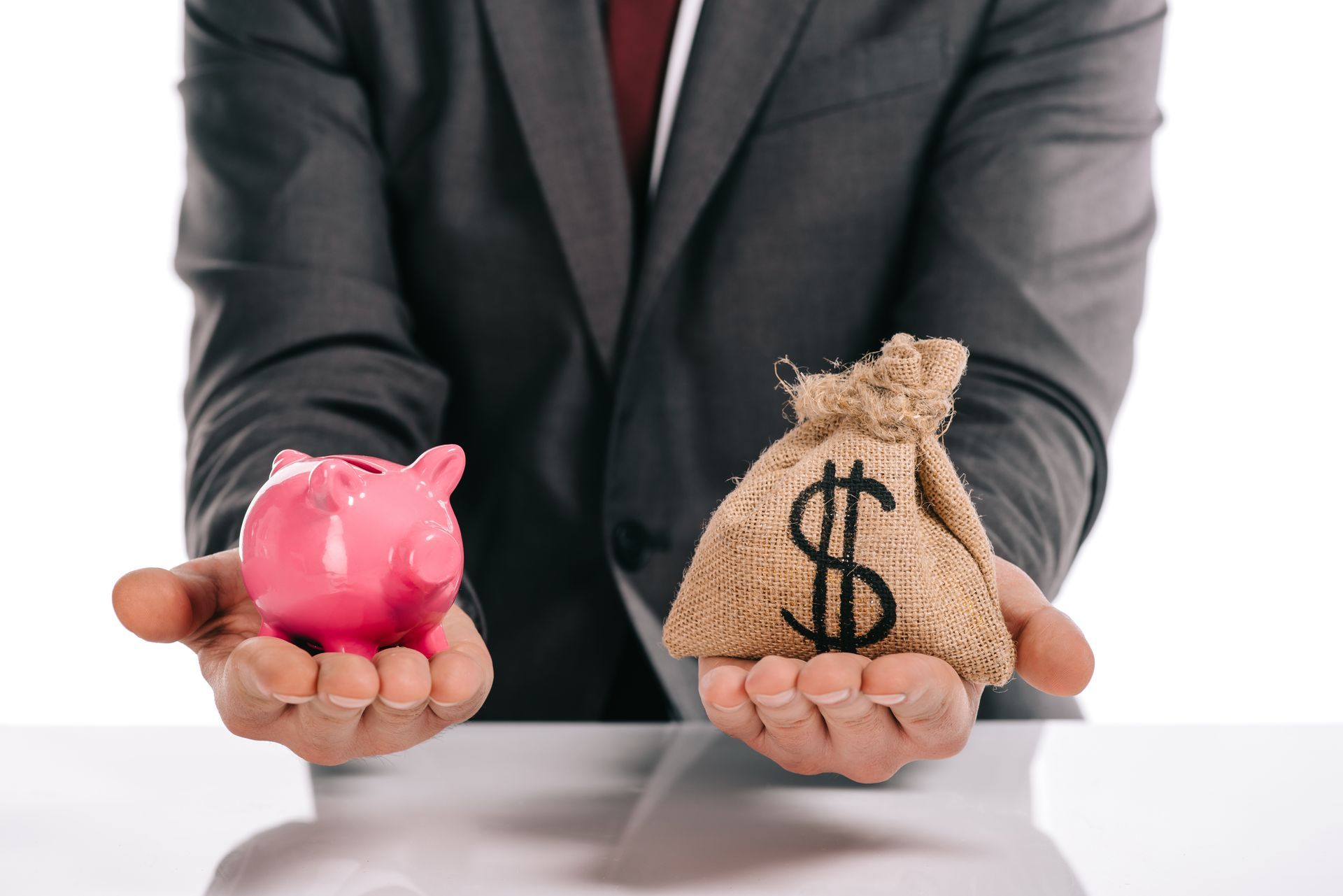 A man in a suit is holding a piggy bank and a bag of money.