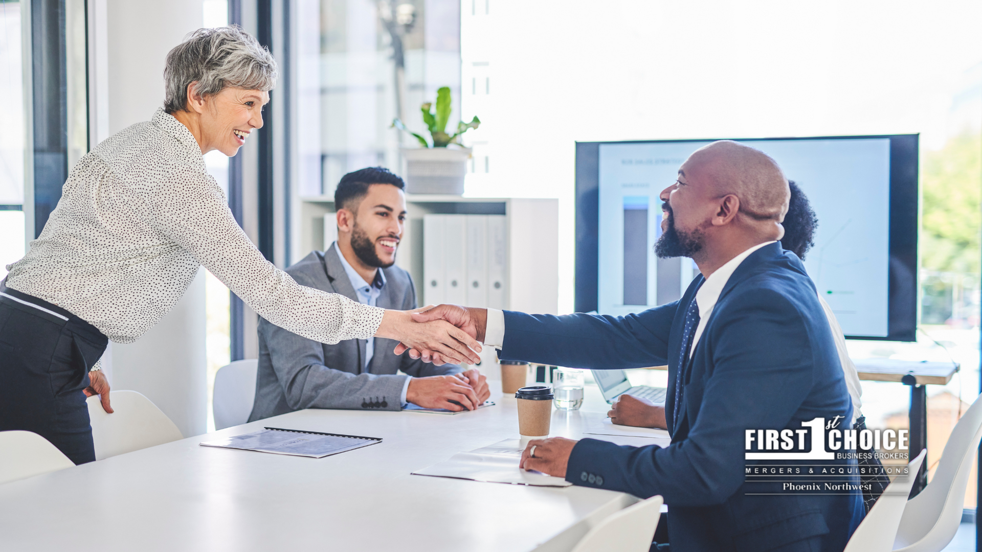 A woman is shaking hands with a man in a conference room.