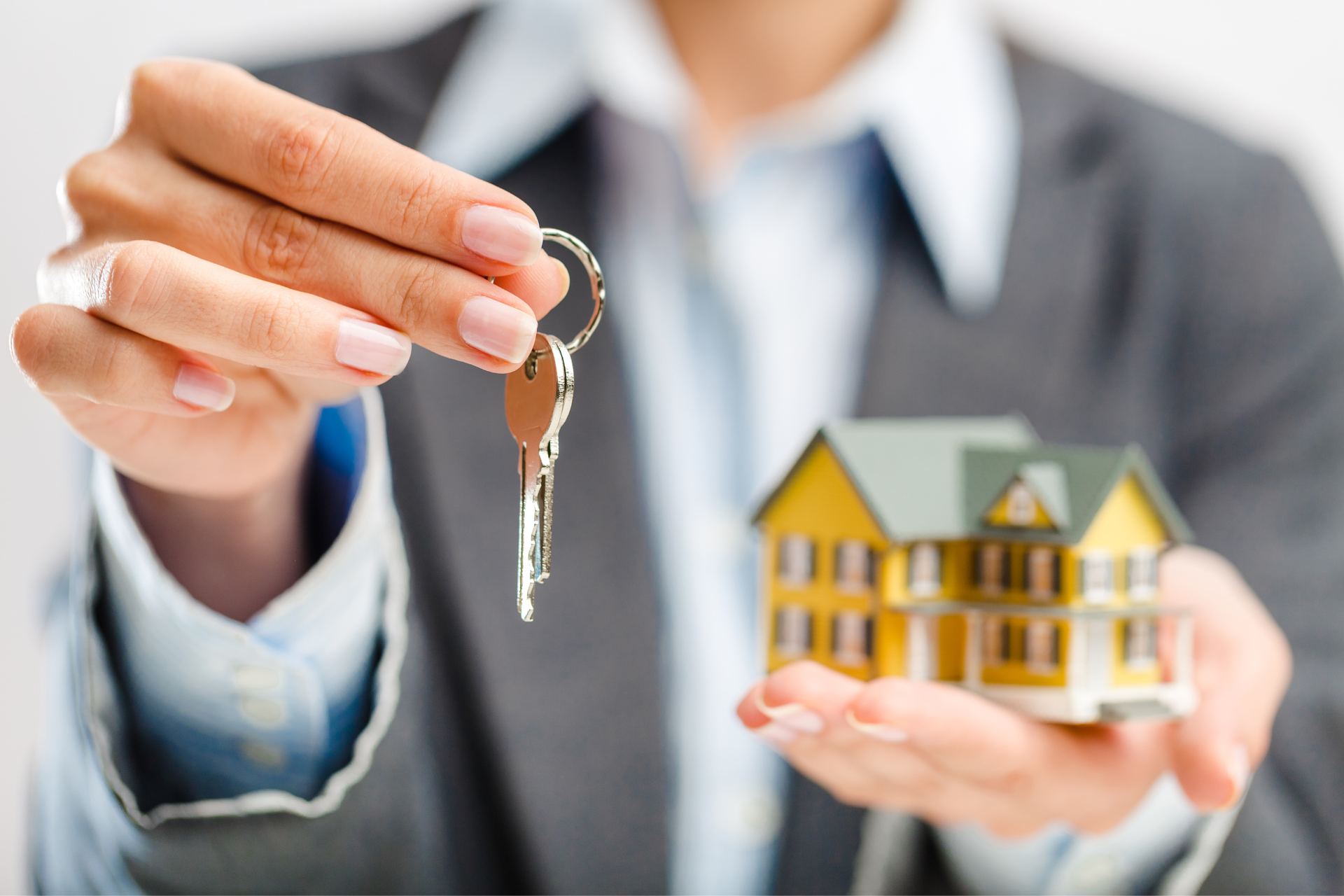 A woman is holding a model house and a key