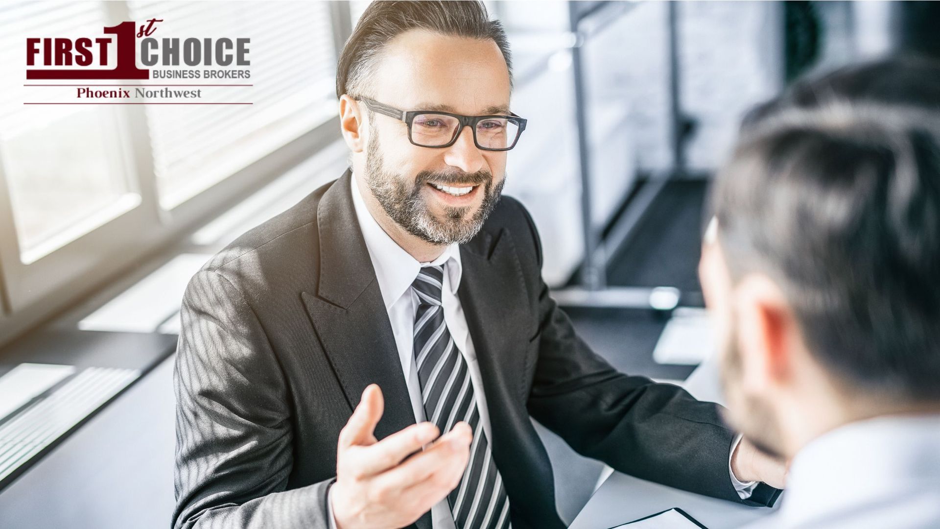A man in a suit and tie is talking to another man.