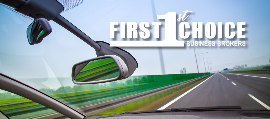 A car is driving down a highway and the rear view mirror is visible.