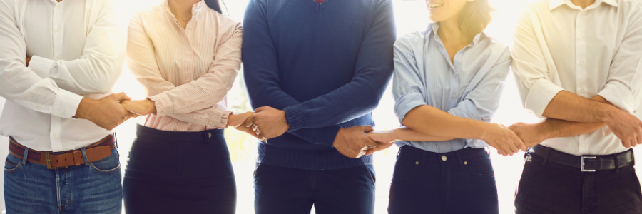 A group of people are standing next to each other with their arms crossed.
