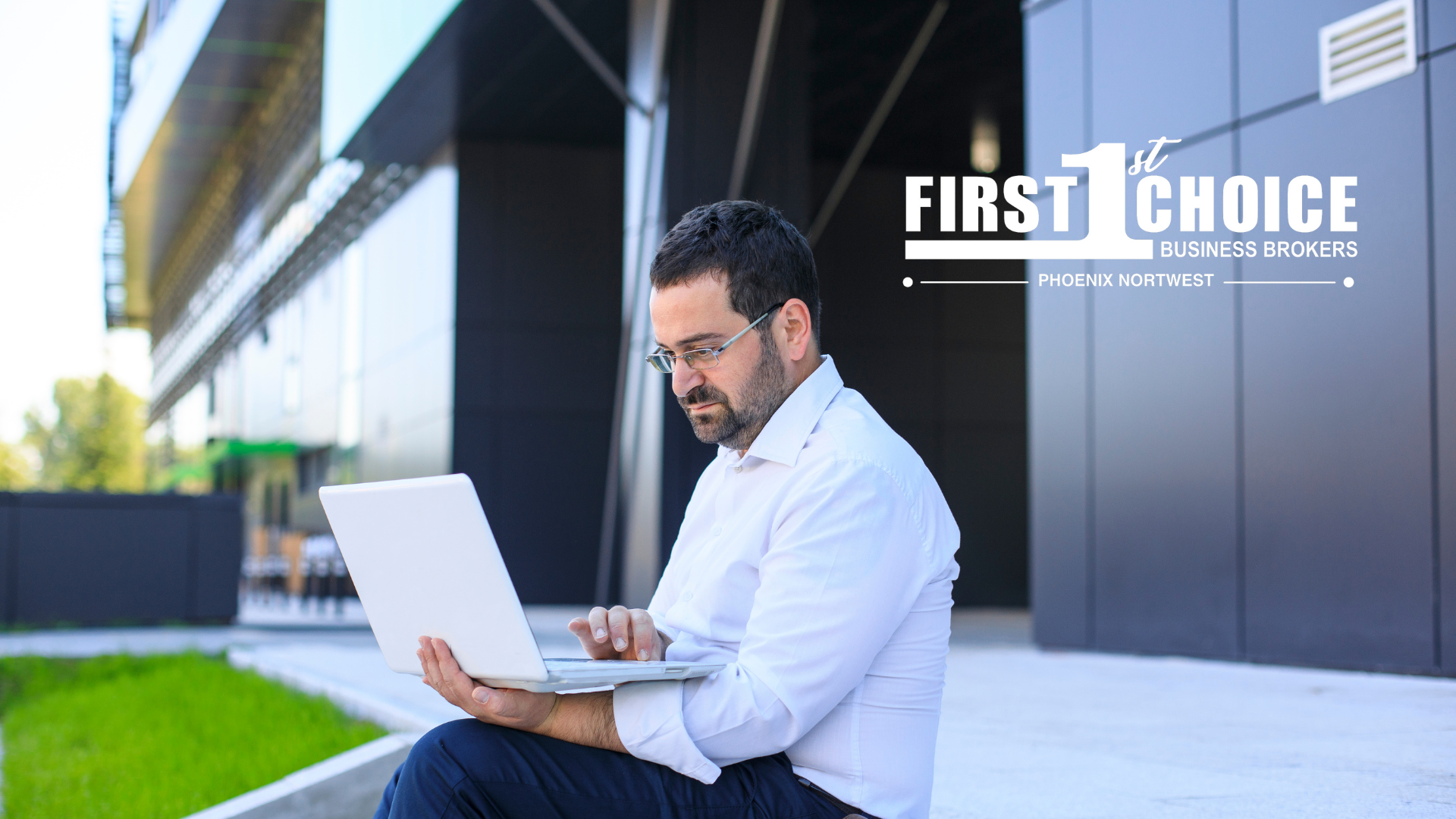 A man is sitting on the sidewalk using a laptop computer.