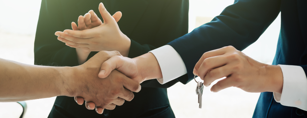 A group of people shaking hands while a man holds a key.
