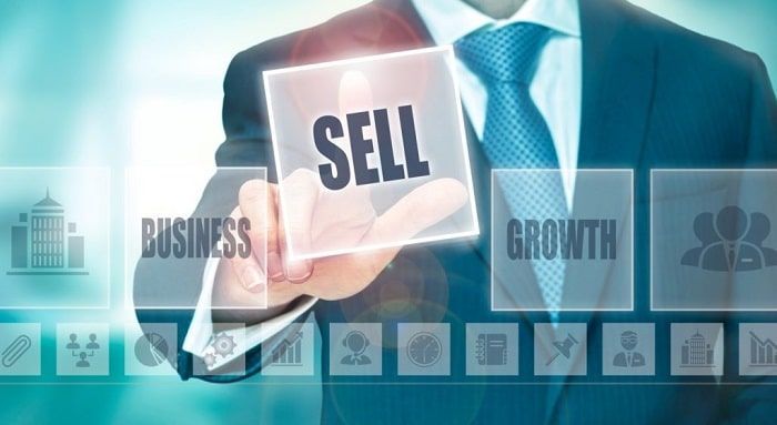 A man in a suit and tie is holding a sign that says sell.