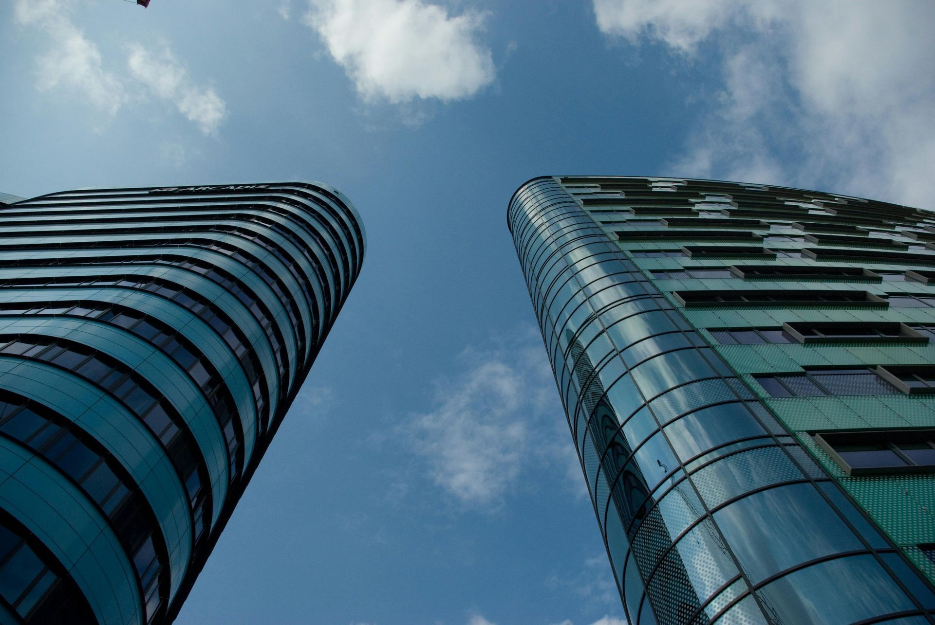 Looking up at two tall buildings with a blue sky in the background