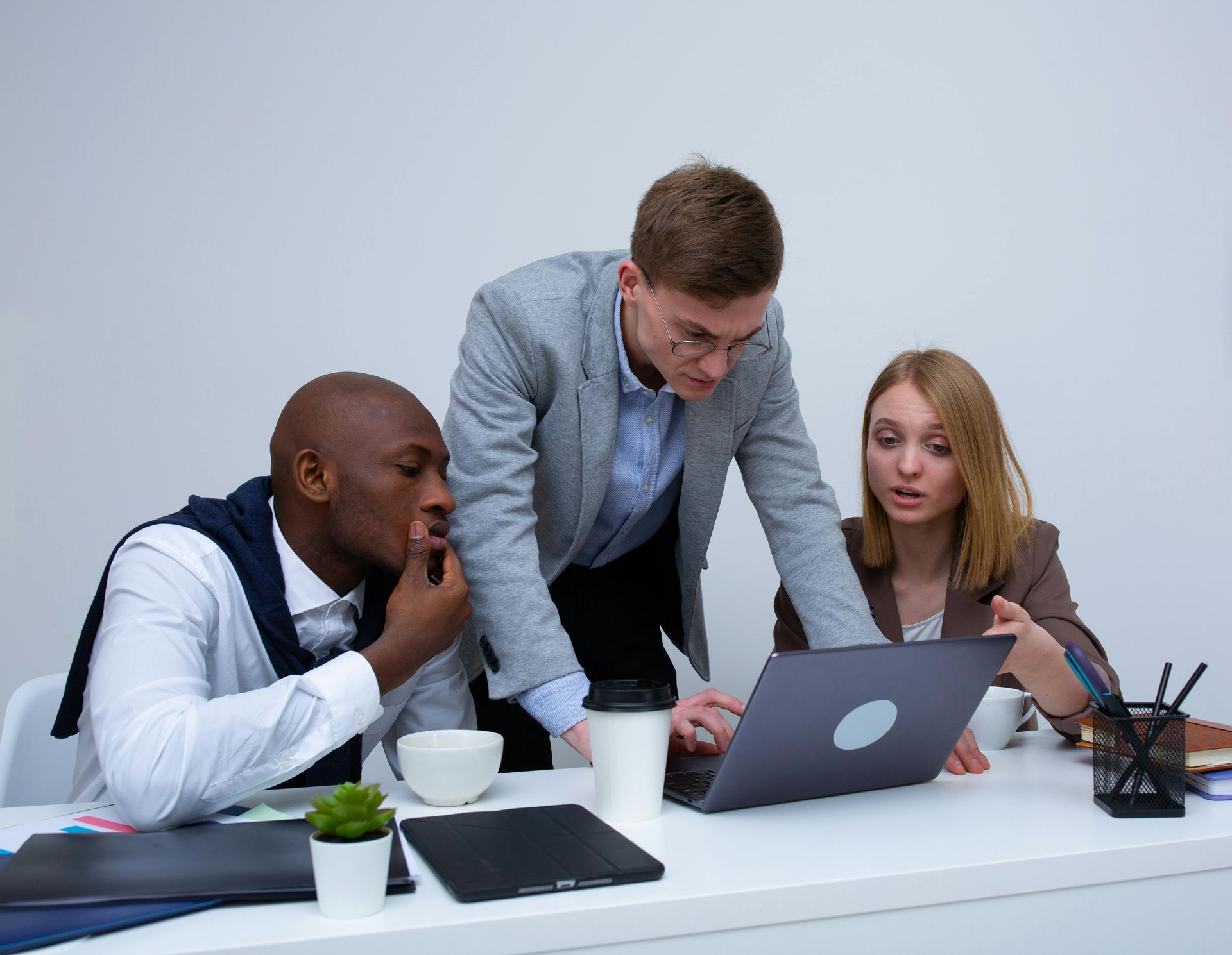 A group of people are sitting at a table looking at a laptop computer.