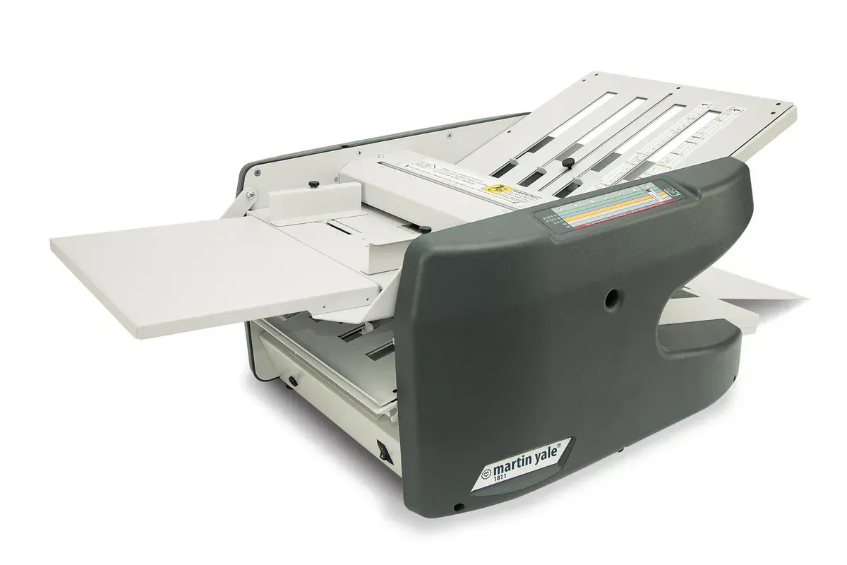 A black and white envelope folding machine is sitting on a white surface