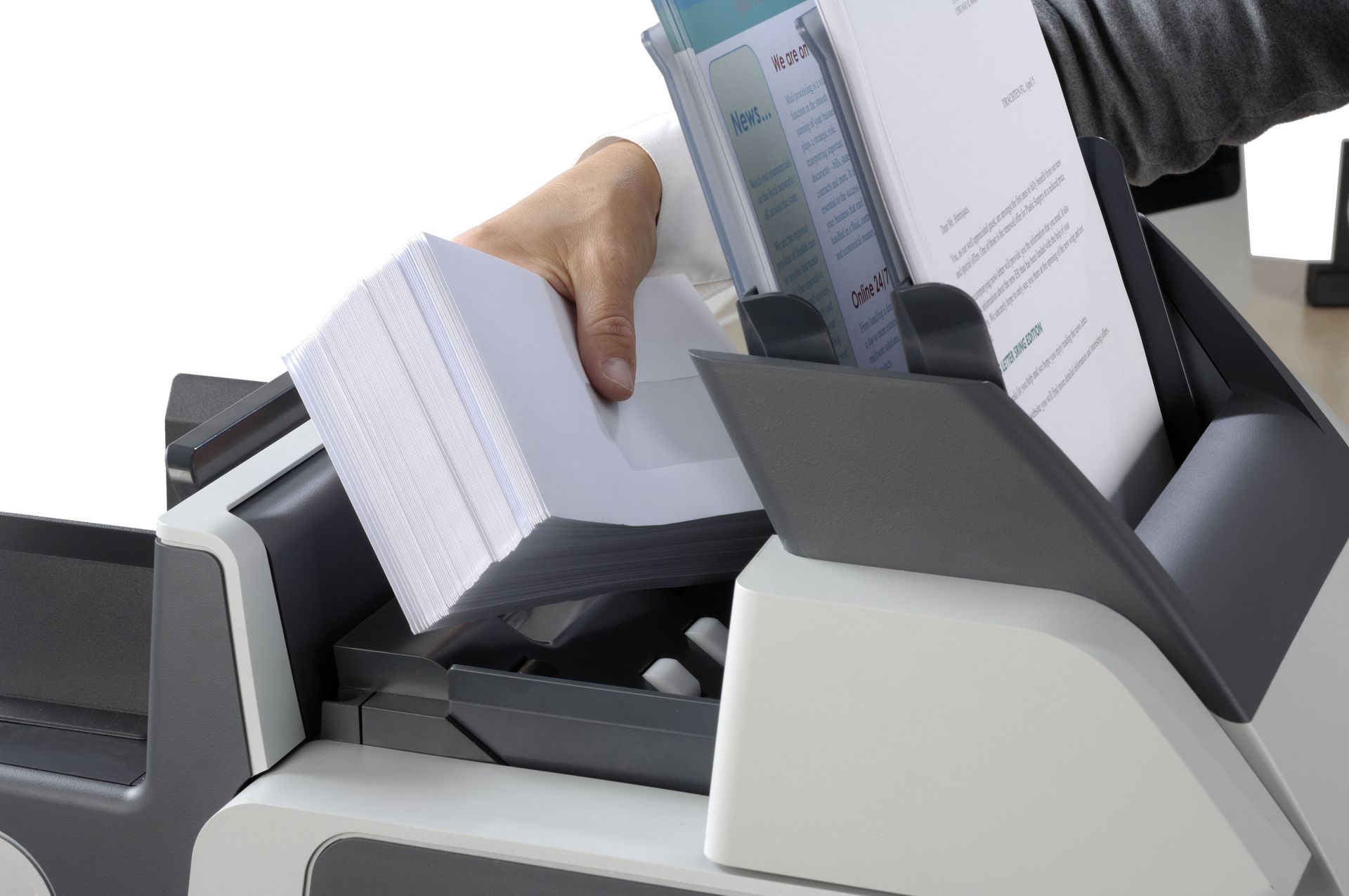 A person is putting a stack of papers into a machine
