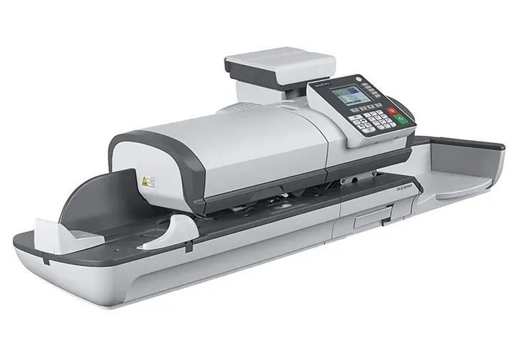 A postage machine is sitting on top of a table on a white background.