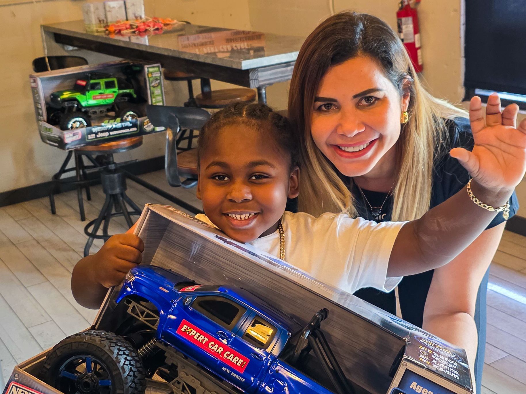 Child and woman smiling and posing with a blue toy truck in a living room