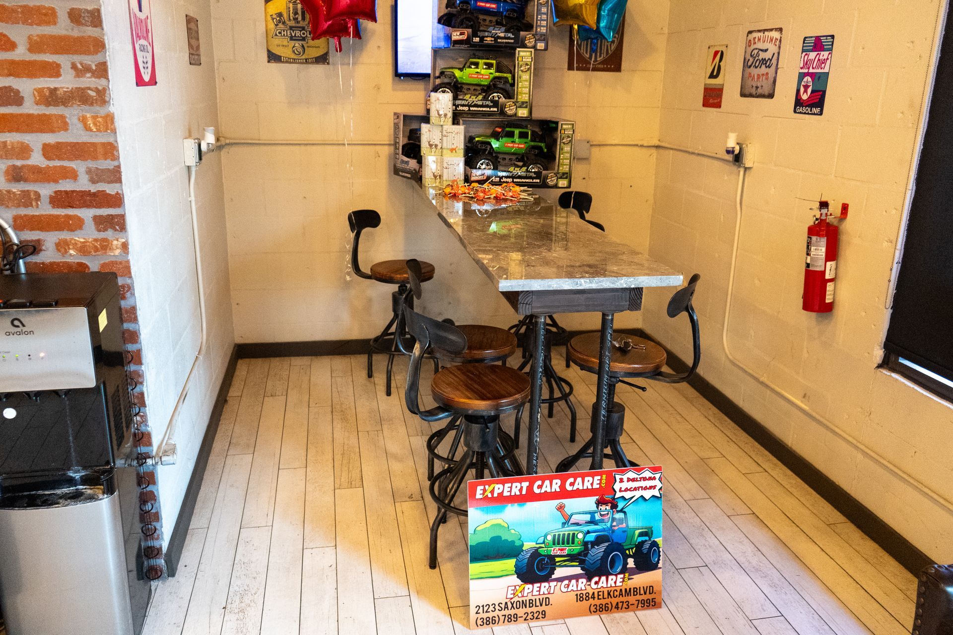 Small café interior with tables, stools, wall art, and a fire extinguisher on the right wall.