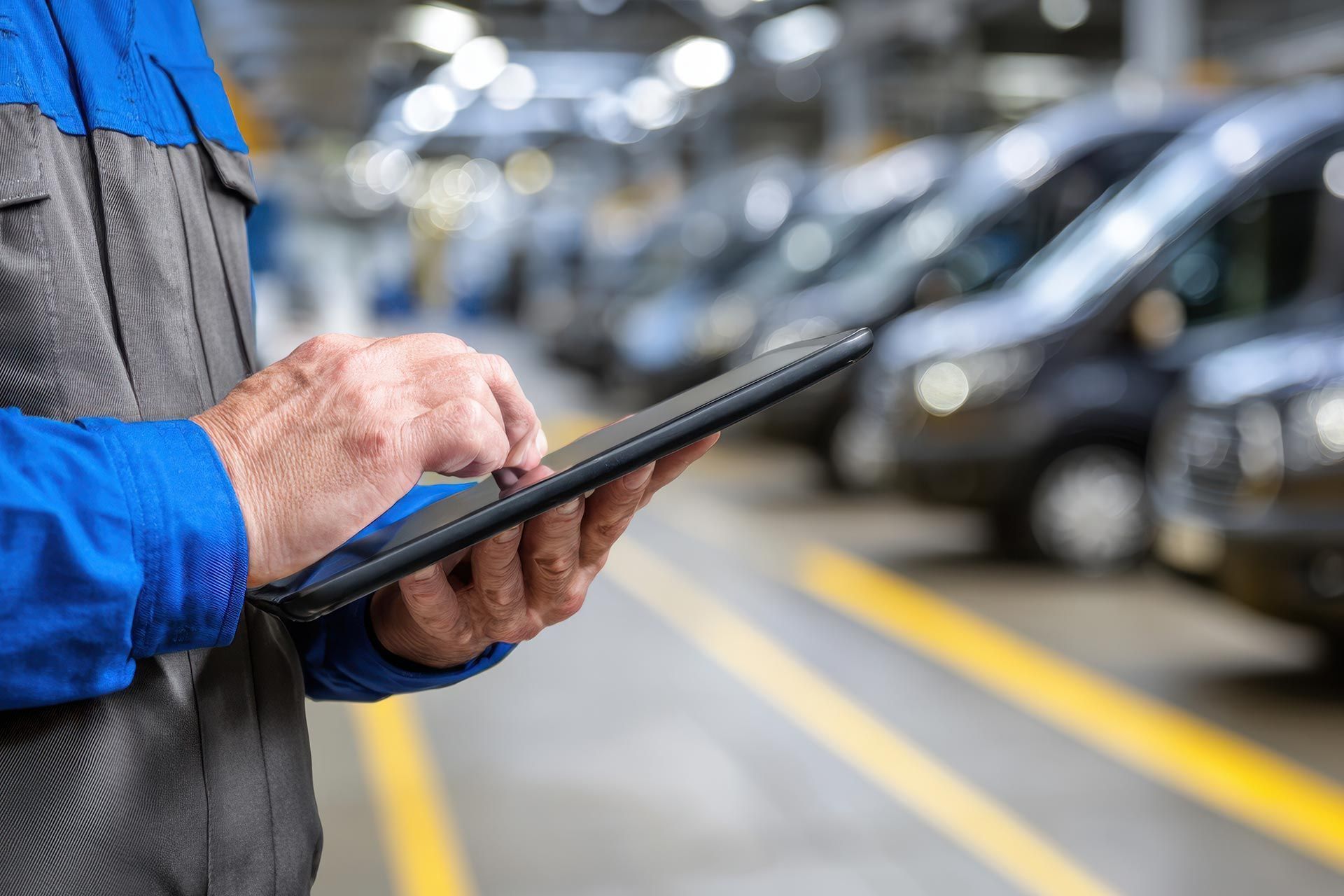 Fleet maintenance technician reviewing service records on a tablet in a commercial vehicle repair facility Fleet maintenance technician reviewing service records on a tablet in a commercial vehicle repair facility