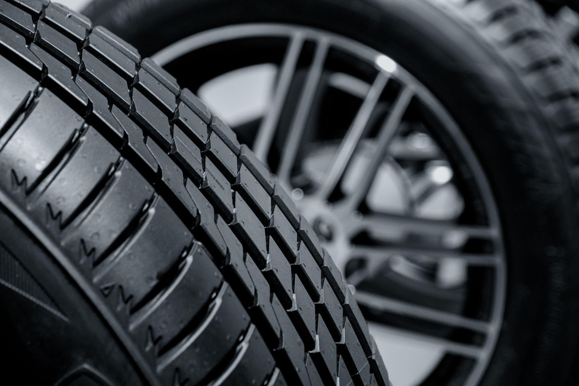 Close-up of car tires with a black tread pattern and blurred alloy wheel in the background