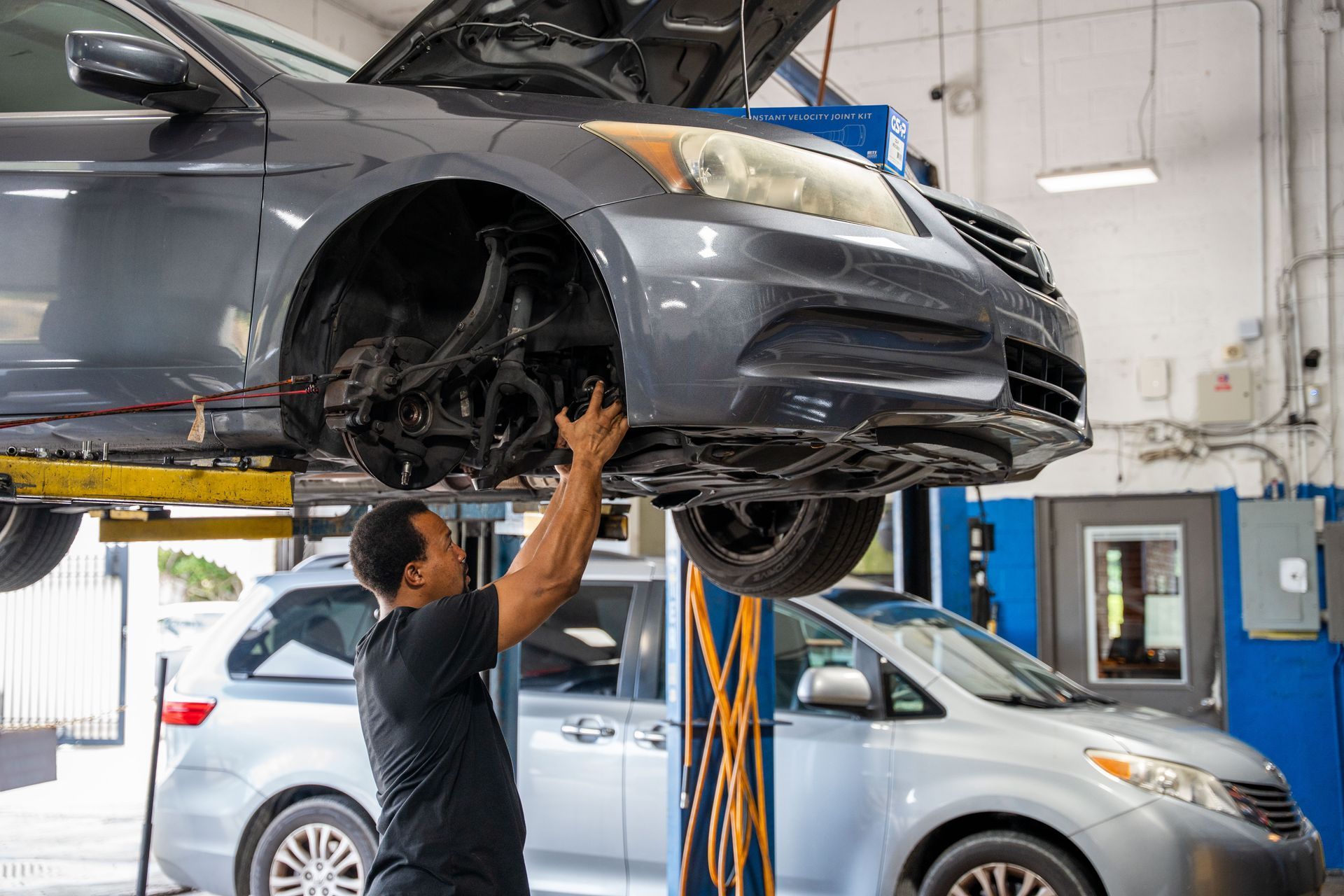 Mechanic inspecting the suspension and brakes of a car on a lift