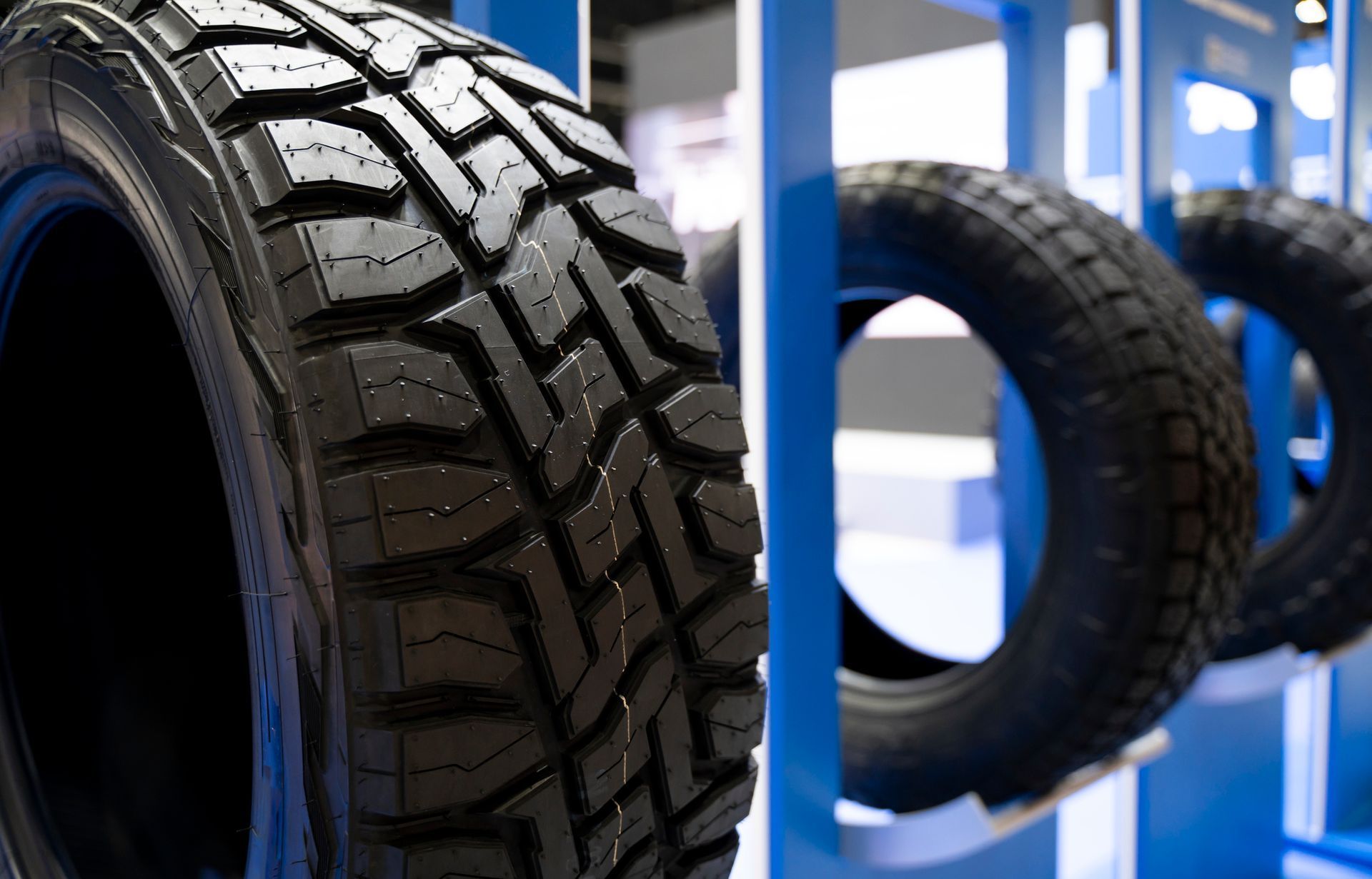 Close-up of black car tires hanging in a shop on blue racks
