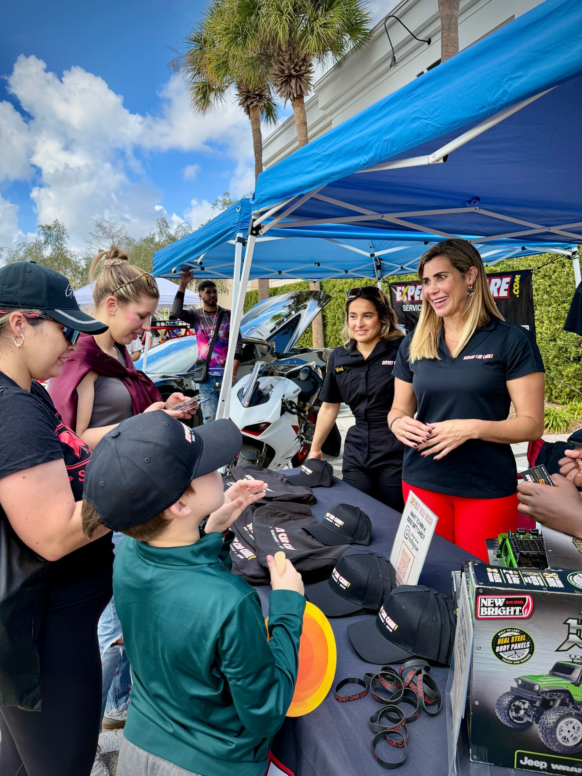 Booth under blue canopy with people browsing hats and apparel outdoors