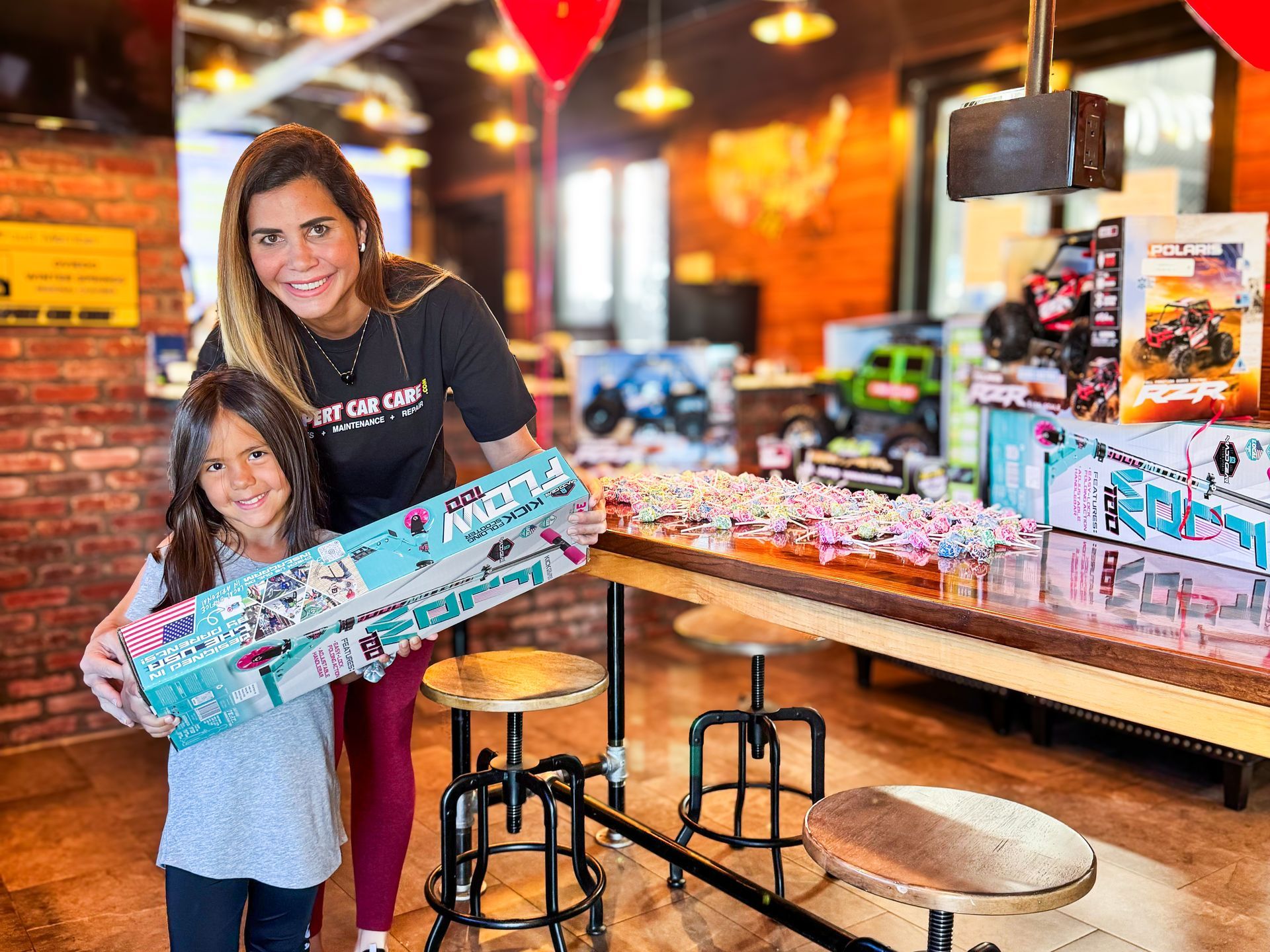 Woman and girl holding a large toy box inside a brightly lit toy store