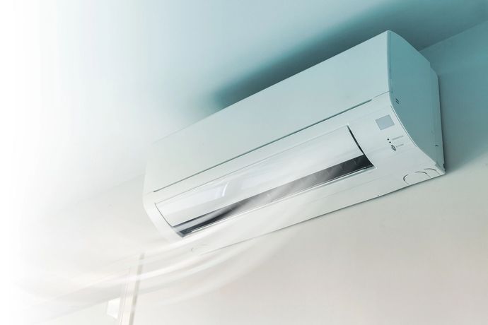 Un condizionatore d'aria bianco a parete che immette aria fresca in una stanza.