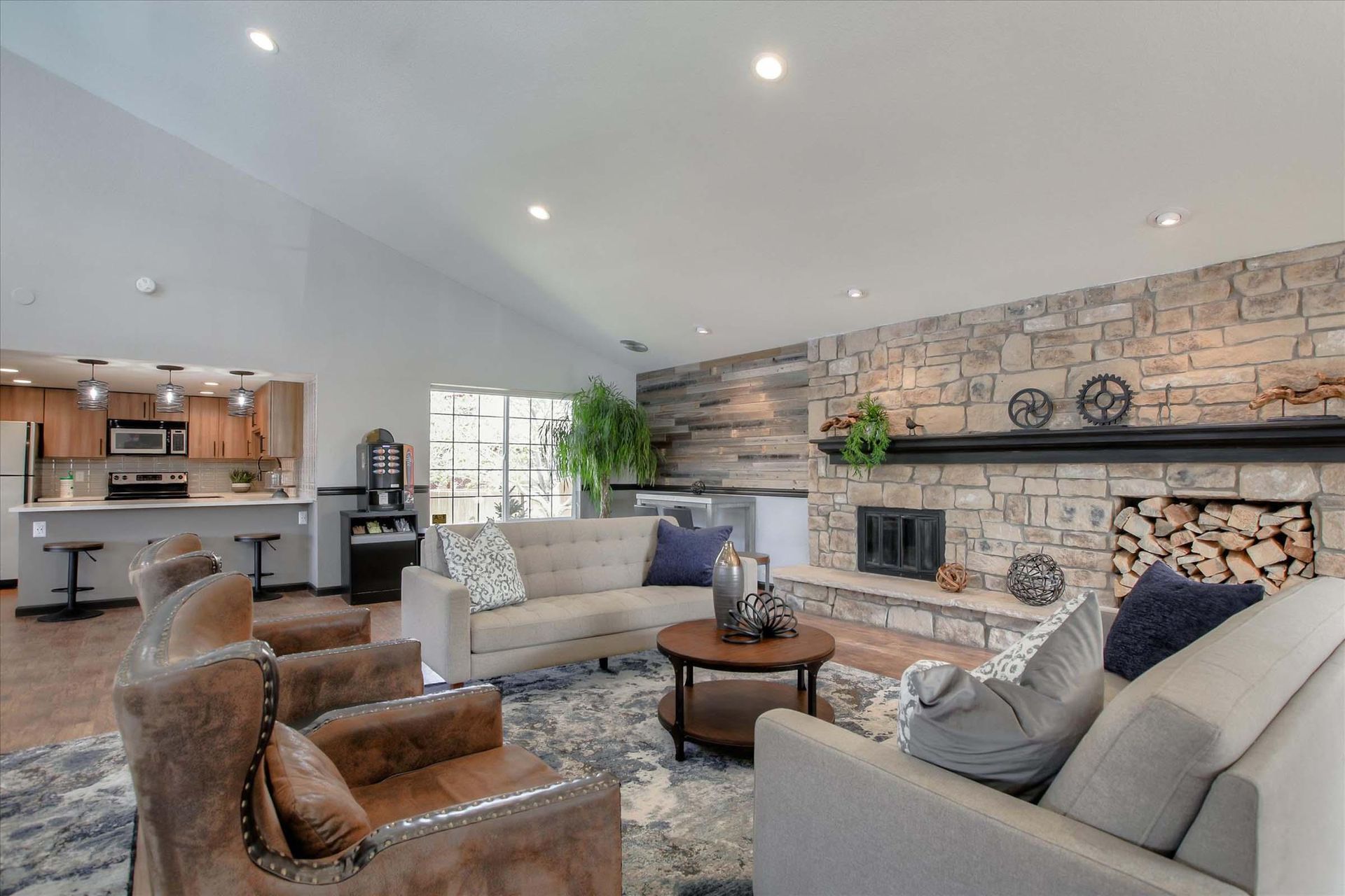 Spacious resident lounge with a stone fireplace, beige couches, and an open kitchen with a bar at Chestnut Ridge Apartment Homes, offers pet-friendly apartments for rent in Denver, CO.