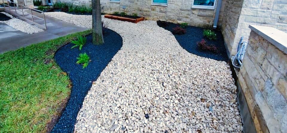 A walkway surrounded by gravel and grass in front of a house.