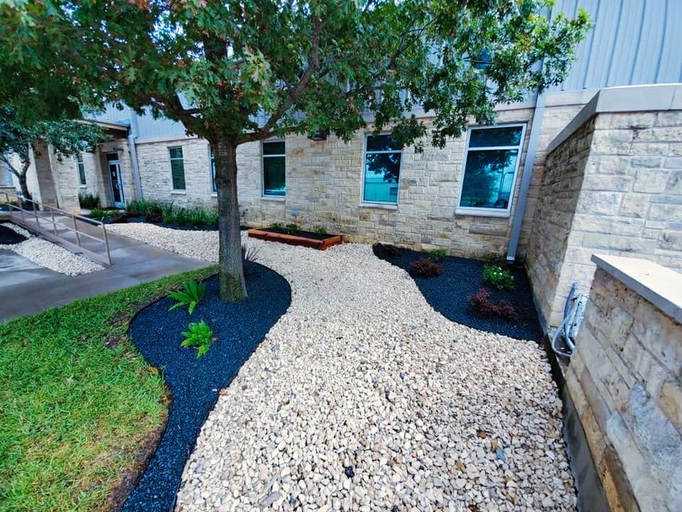 A gravel path leading to a building with a tree in the background.