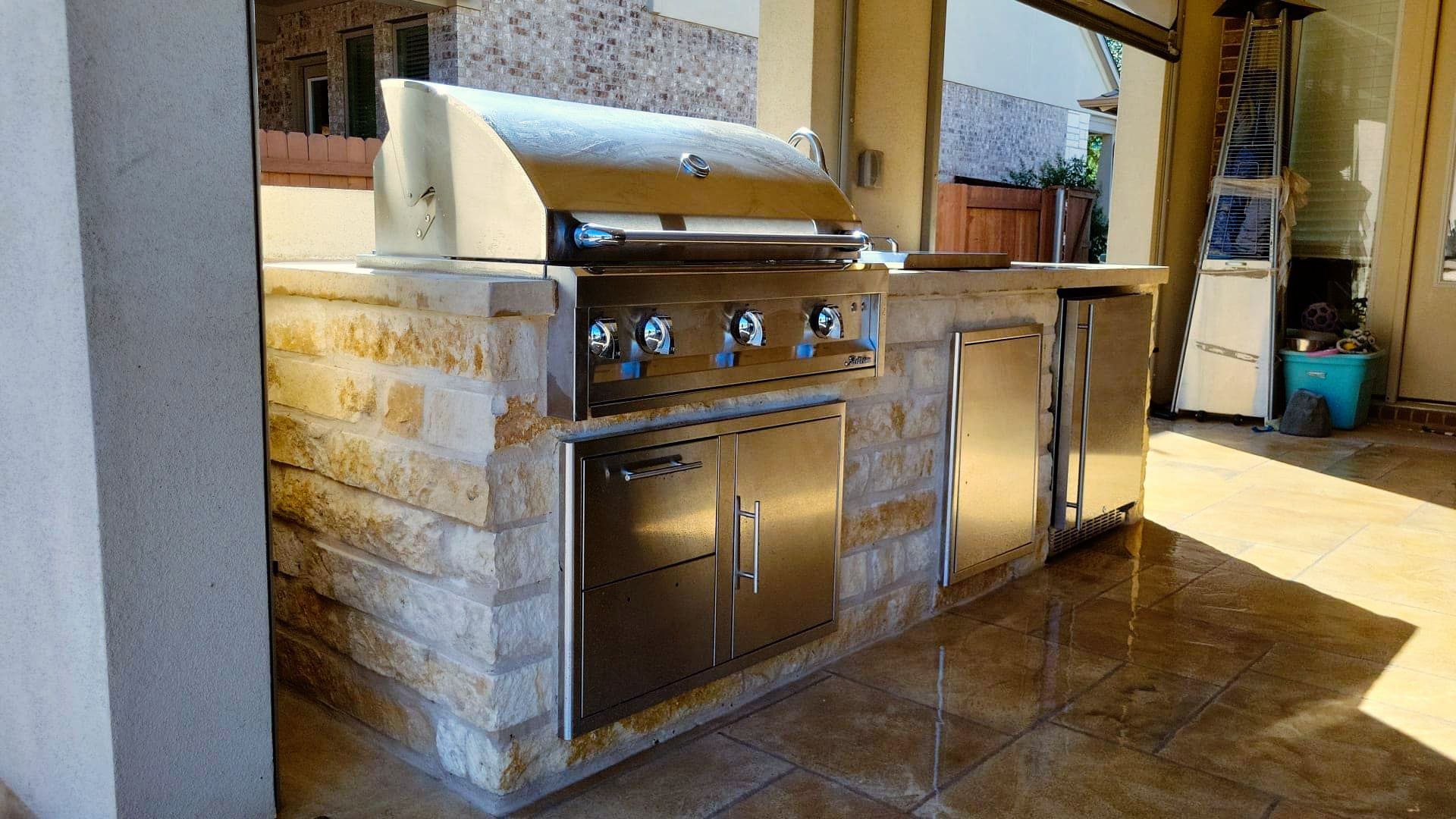 A stainless steel grill is built into a stone wall in a kitchen.