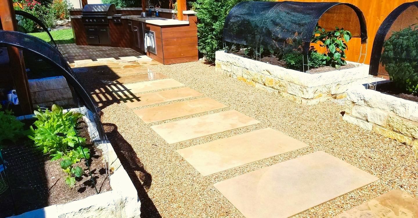 A stone walkway leading to a kitchen in a backyard.