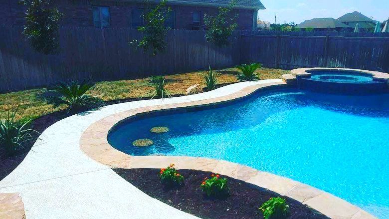 A large swimming pool with a walkway leading to it in a backyard.