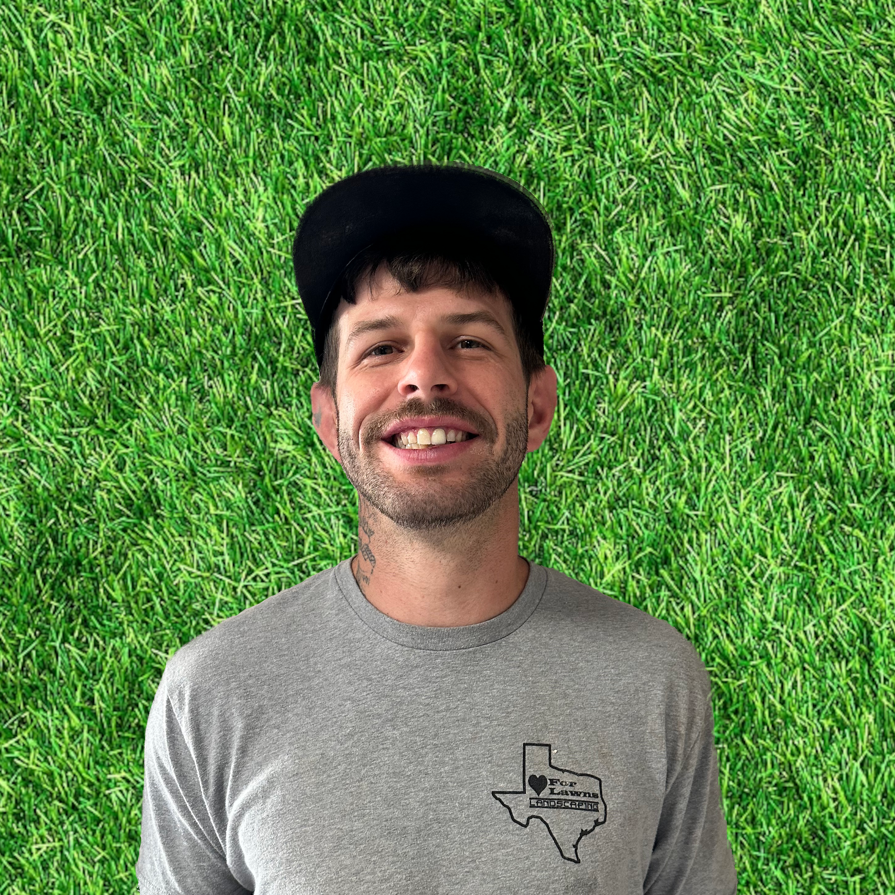 A man wearing a hat and a gray shirt is smiling in front of a green background.