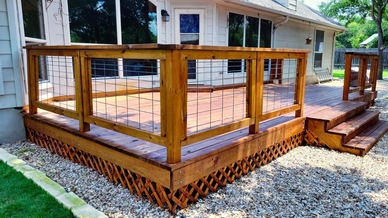 A wooden deck with stairs and a fence in front of a house.