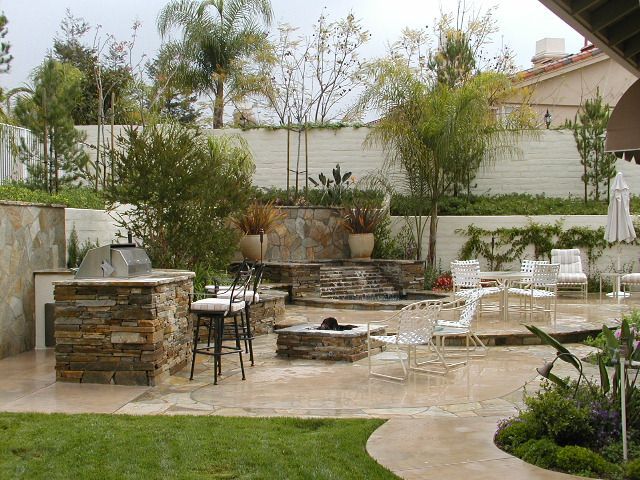 Backyard patio with stone fire pit, outdoor seating, and a wet patio after rain