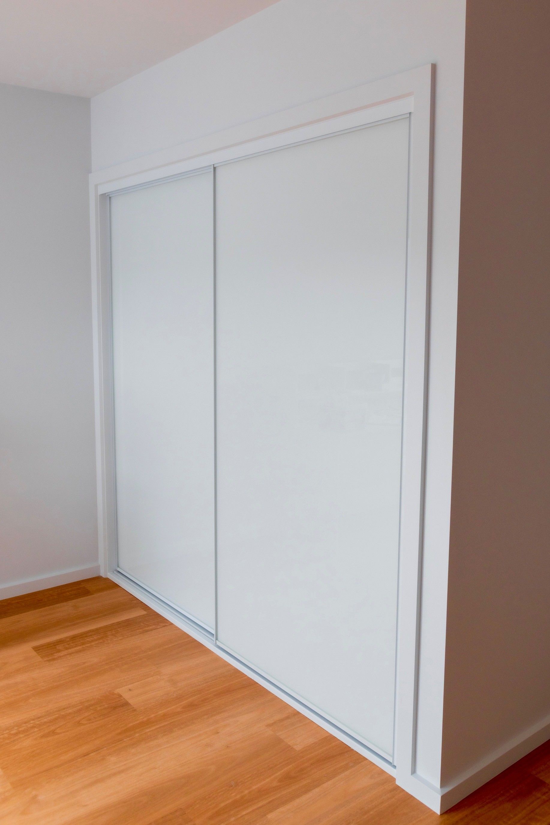 White sliding closet doors in a room with light walls and hardwood floor