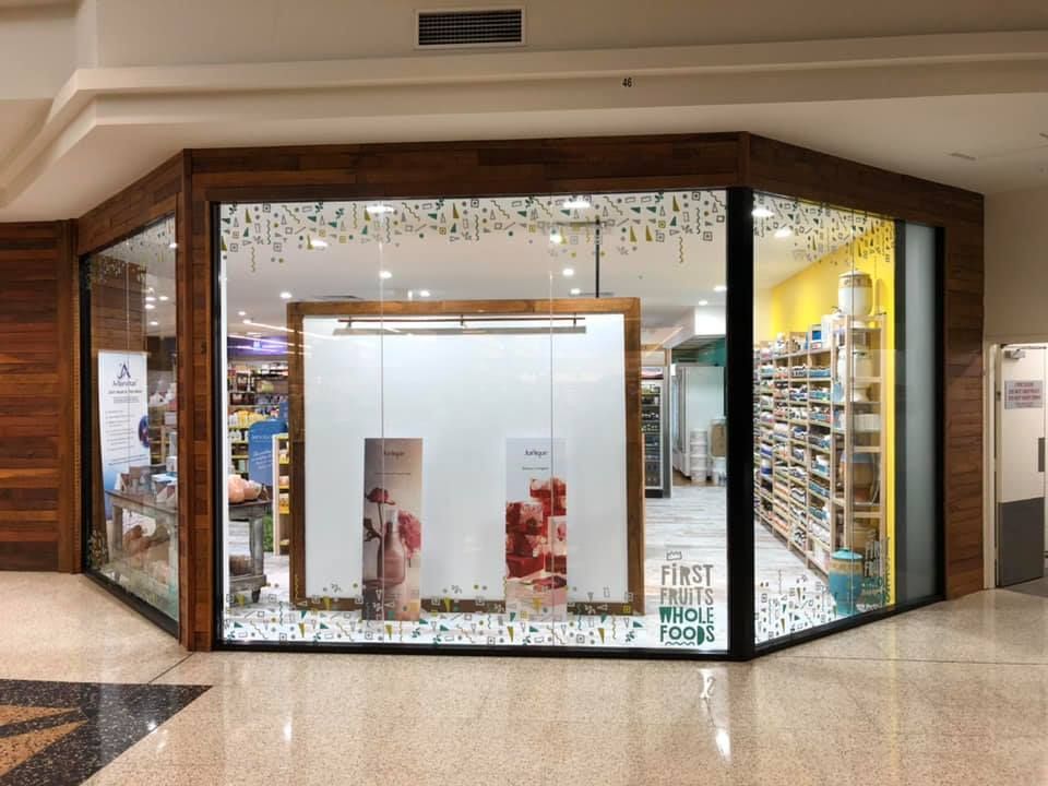 Empty storefront kiosk with glass display windows and white interior in a mall corridor