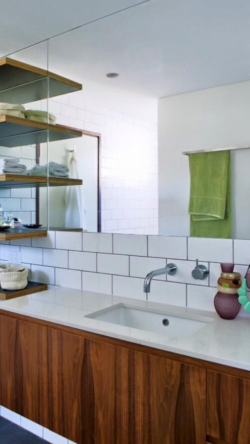 Modern kitchen with wood cabinets, white tile backsplash, open shelves, and green towel by the sink