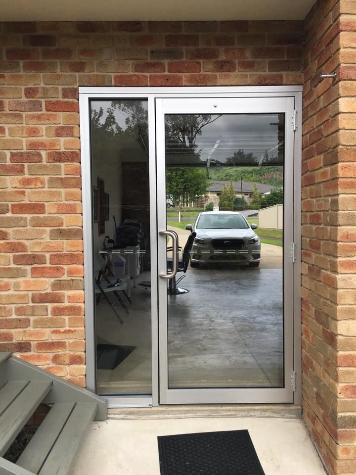 Sliding glass patio door on a brick porch, reflecting a car parked in the driveway.