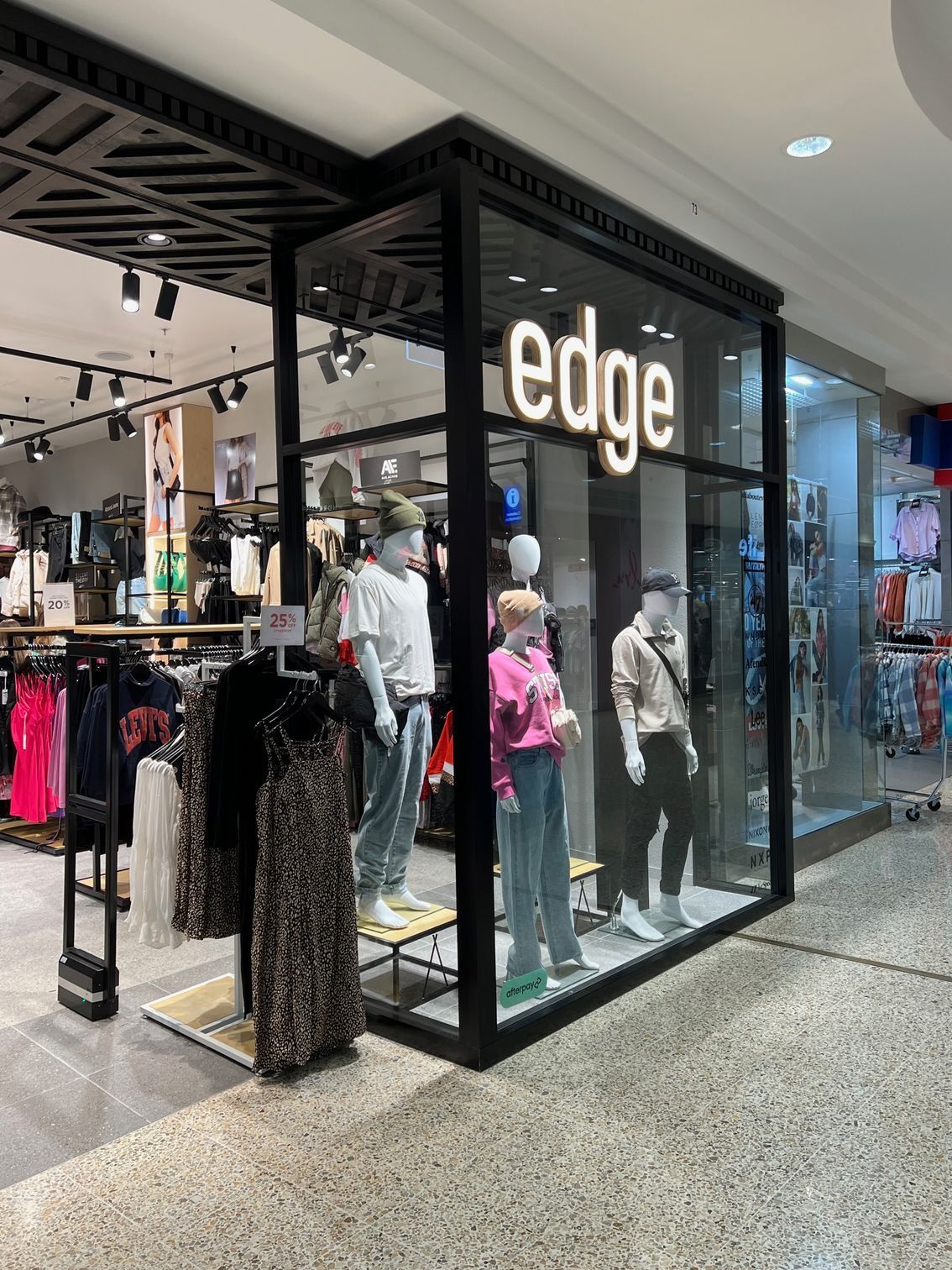 Storefront display for Edge clothing shop with mannequins and hanging garments in a mall corridor