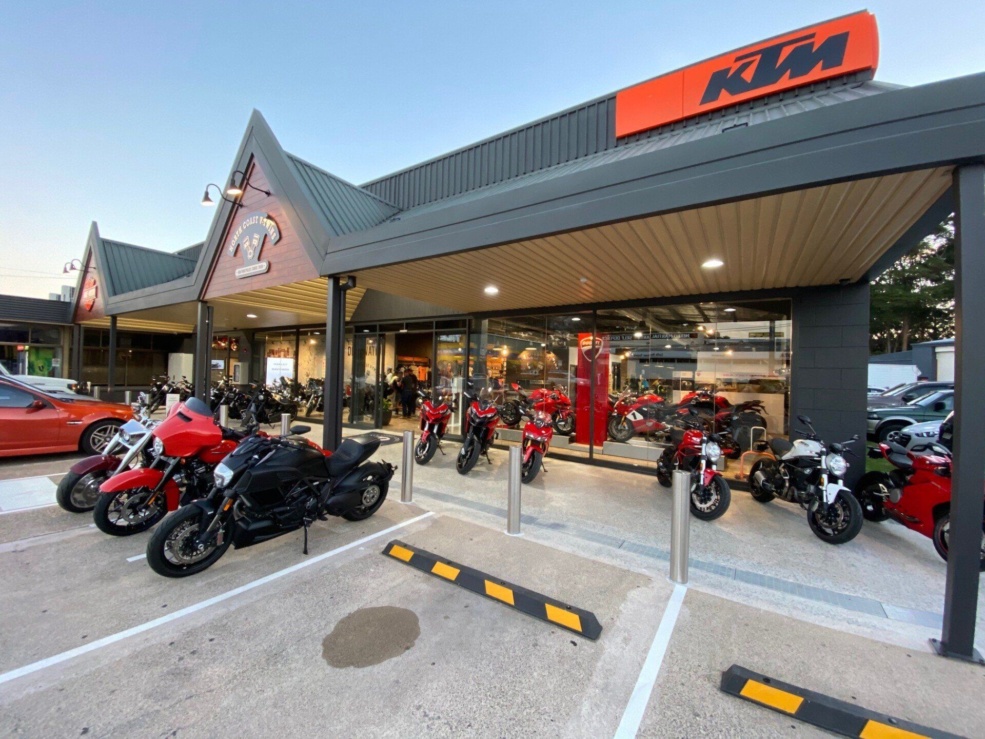 KTM motorcycle dealership exterior with several bikes parked outside under a covered entrance