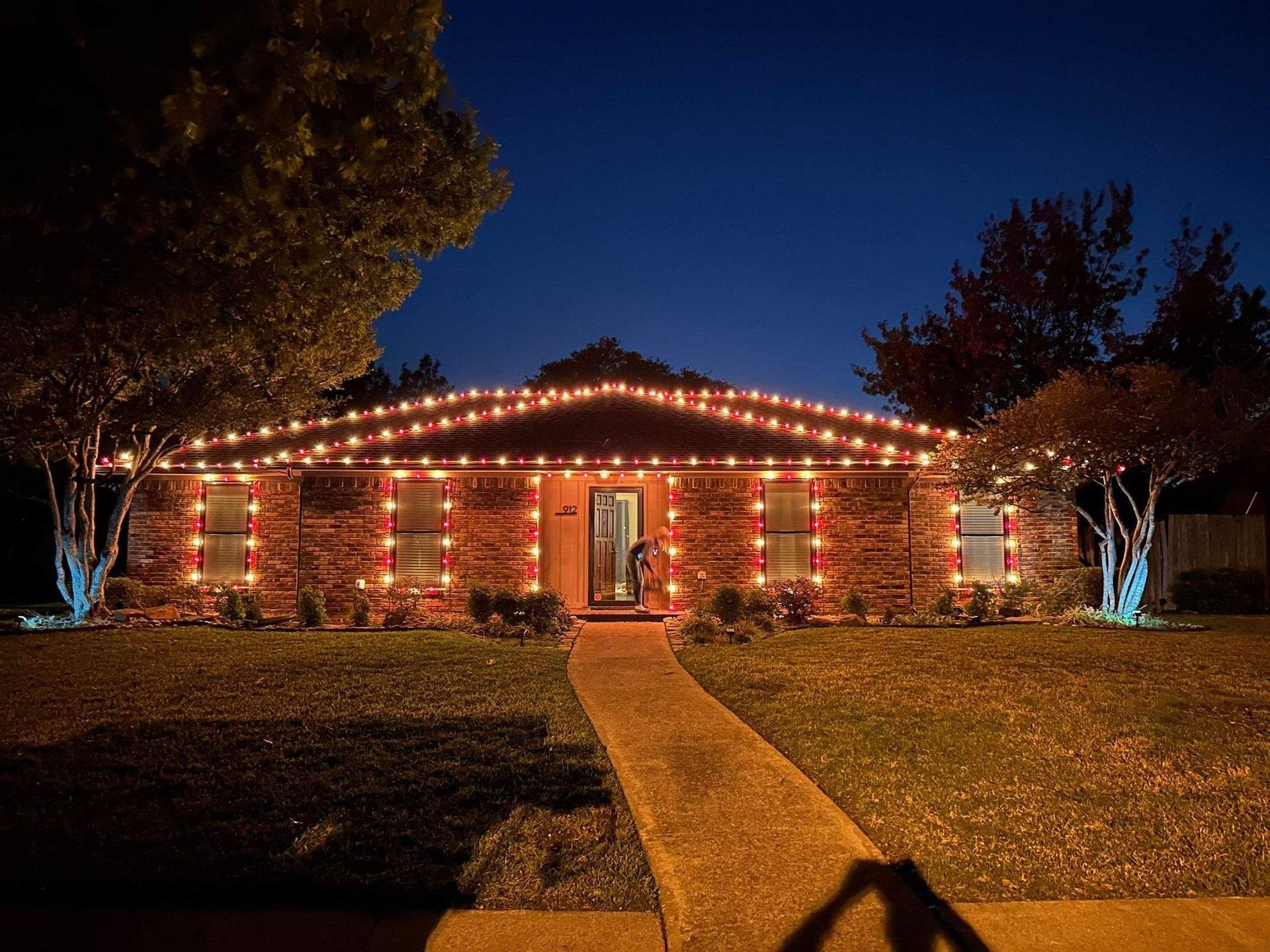 A brick house is decorated with christmas lights at night.