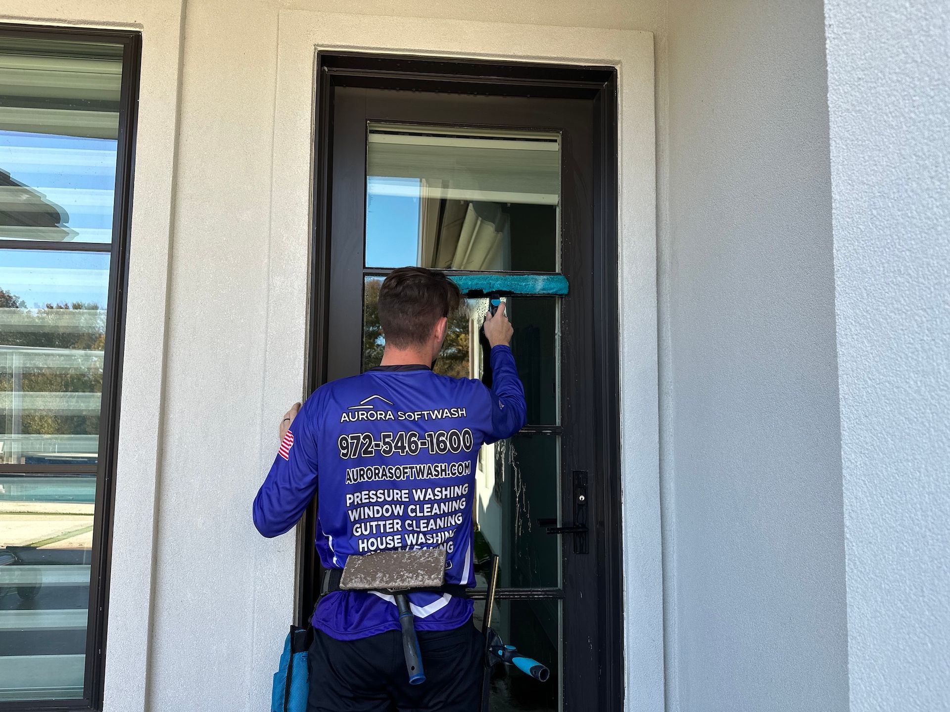 A man is cleaning a glass door with a squeegee.