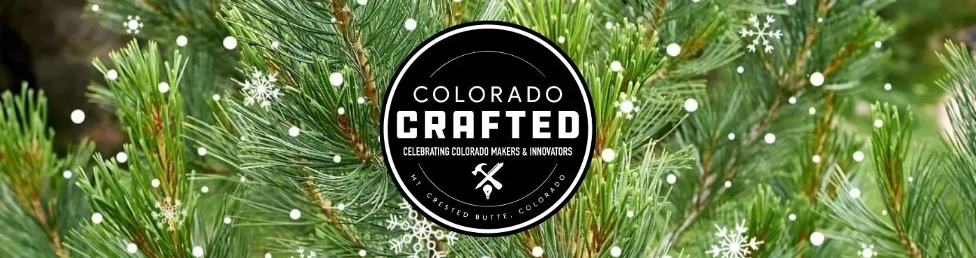 Christmas tree branches with the words Colorado Crafted in a black circle.