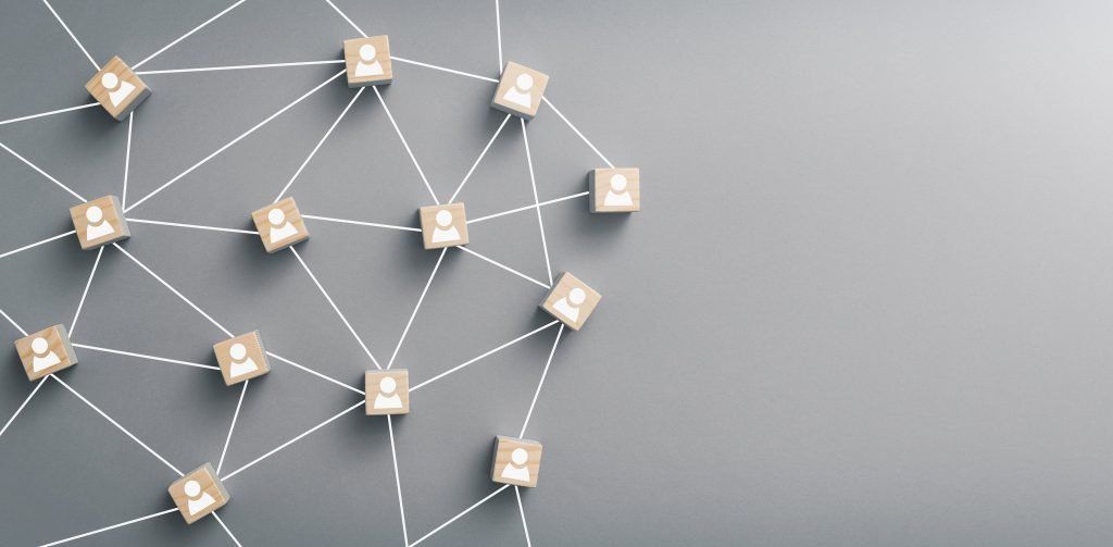 Network of wooden blocks with person icons, connected by white lines, on a gray background.