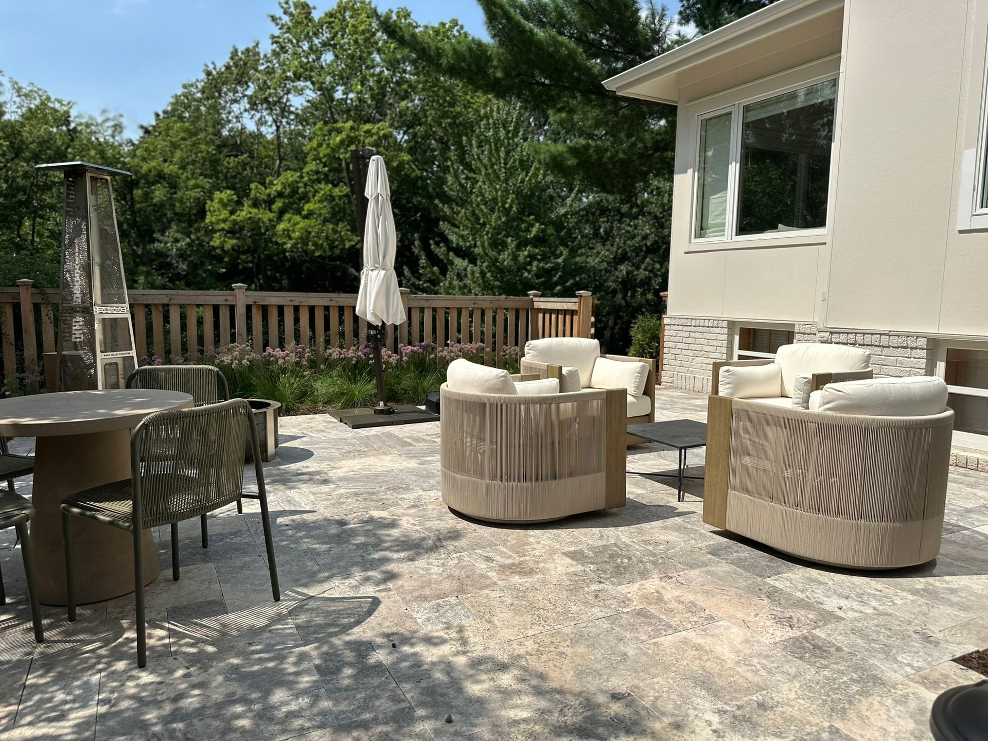 Outdoor sitting area in Minneapolis backyard with stone faced steps and modern hand railing natural stone travertine  pavers new fence plantings cozy seating 
