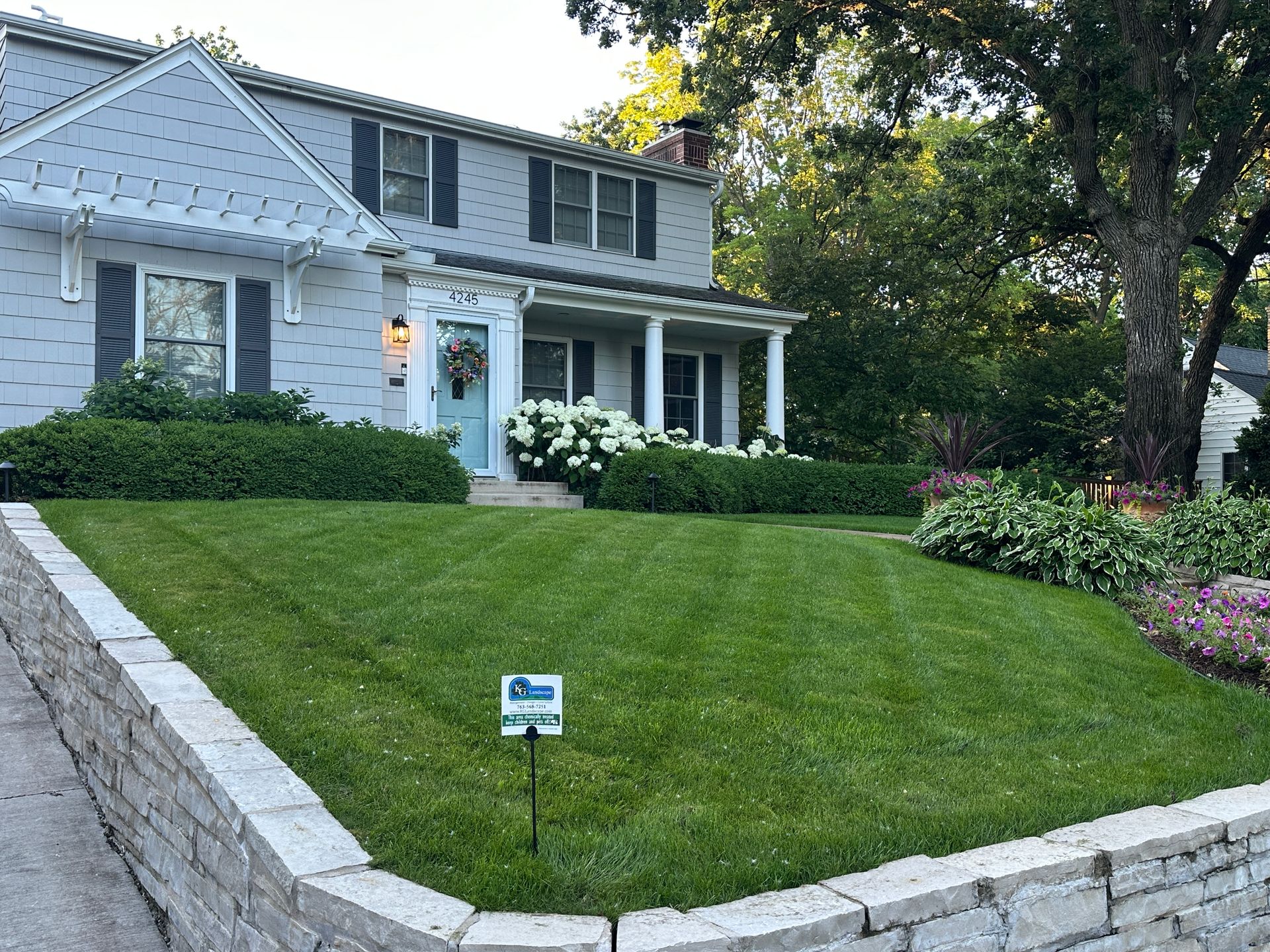 Nice looking gray house in St. Louis Park MN with thick green lawn and a KG Landscape fertilizer sign in the grass