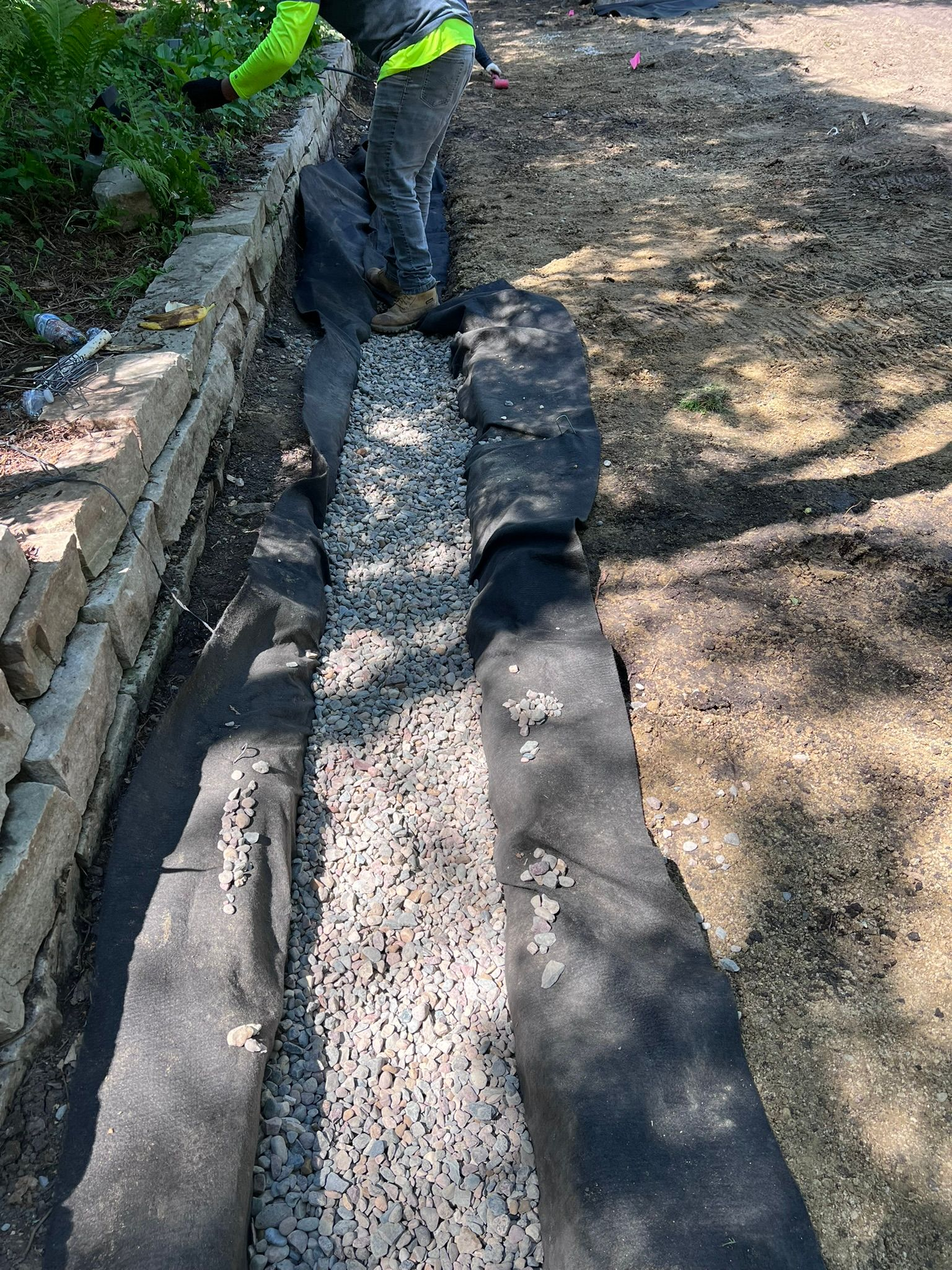 KG Landscape installing a French drain in Edina MN backfilled with gravel in a trench lined with filtration fabric 