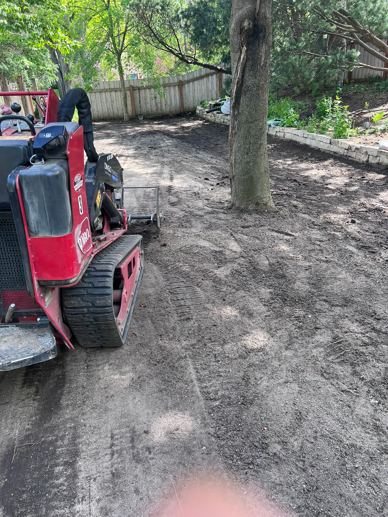 toro dingo machine grading topsoil to smooth a backyard before seeding 