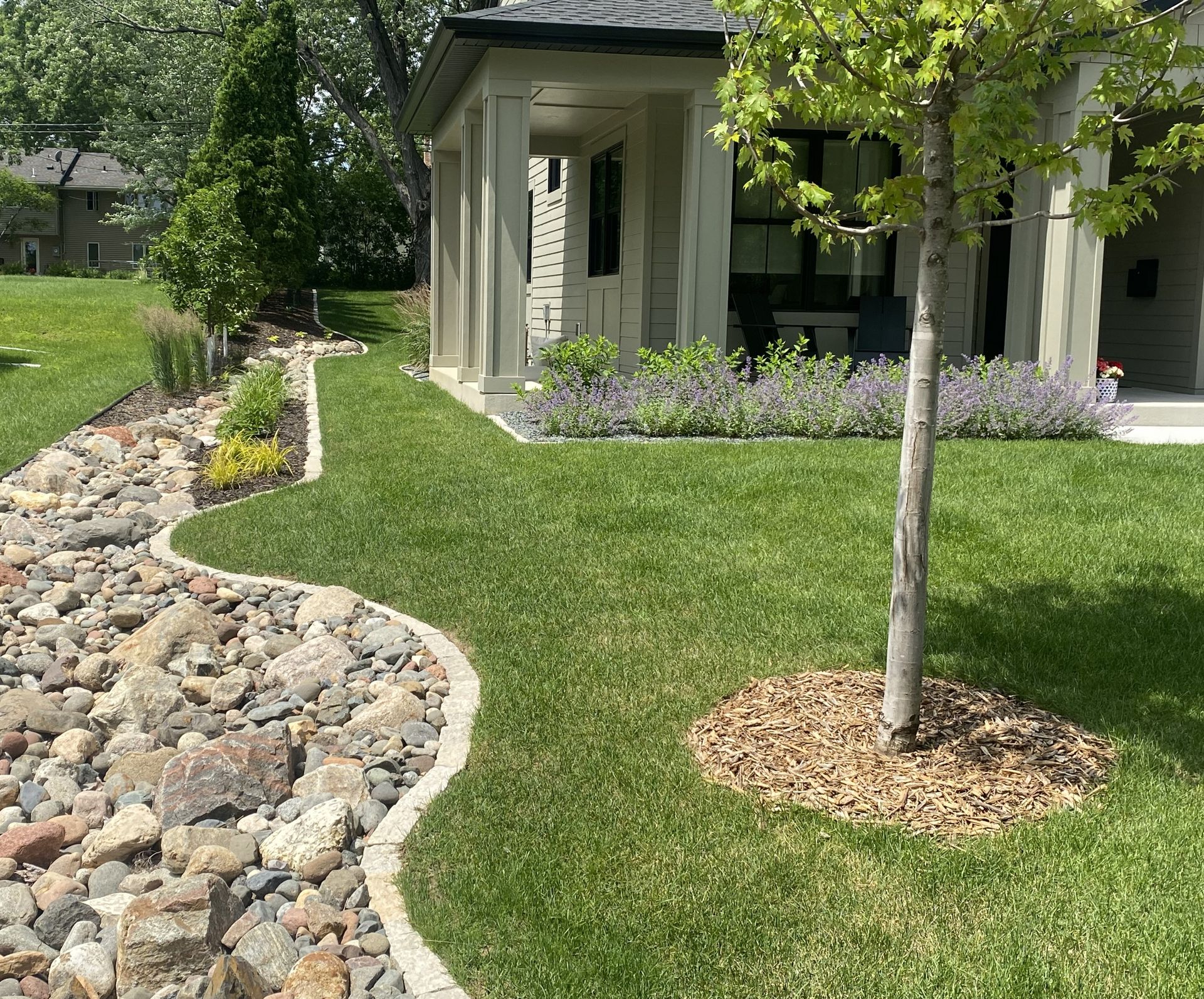 A house is surrounded by trees and rocks in a garden.